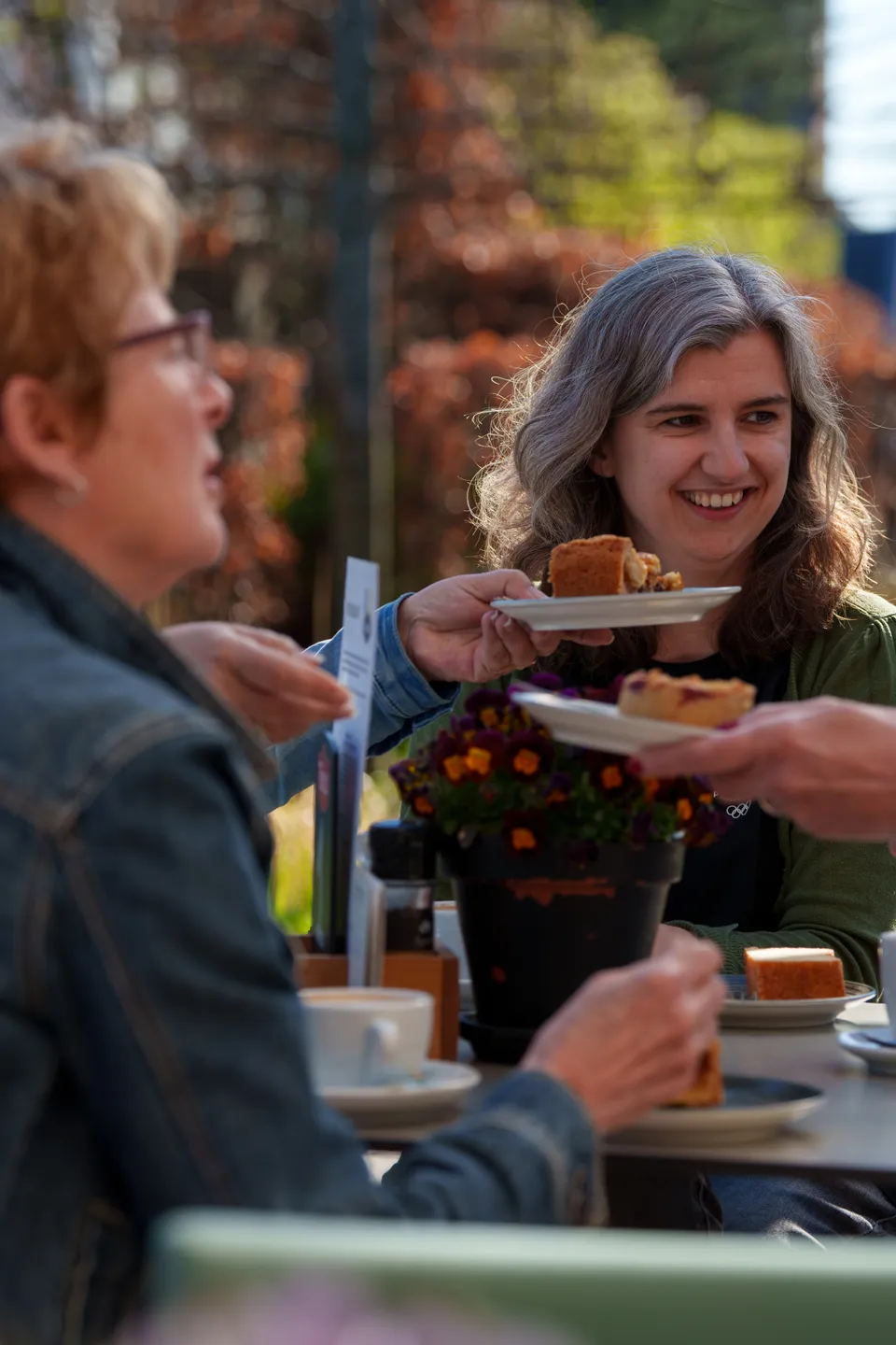 Gasten delen taart en koffie op het zonnige terras van Kiki