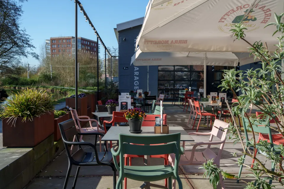 Kiki&rsquo;s terras met kleurrijke stoelen, bloemen en parasols